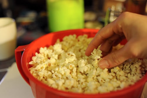 Caucasian Person's Hand in Red Bowl of Popping Corn